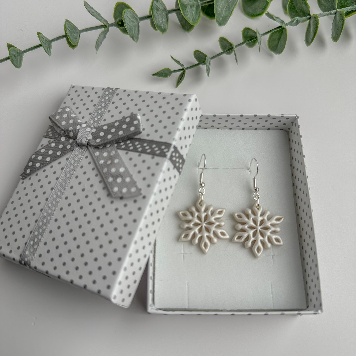 Handmade white polymer clay snowflake earrings in a gift box by Purely Clayful.