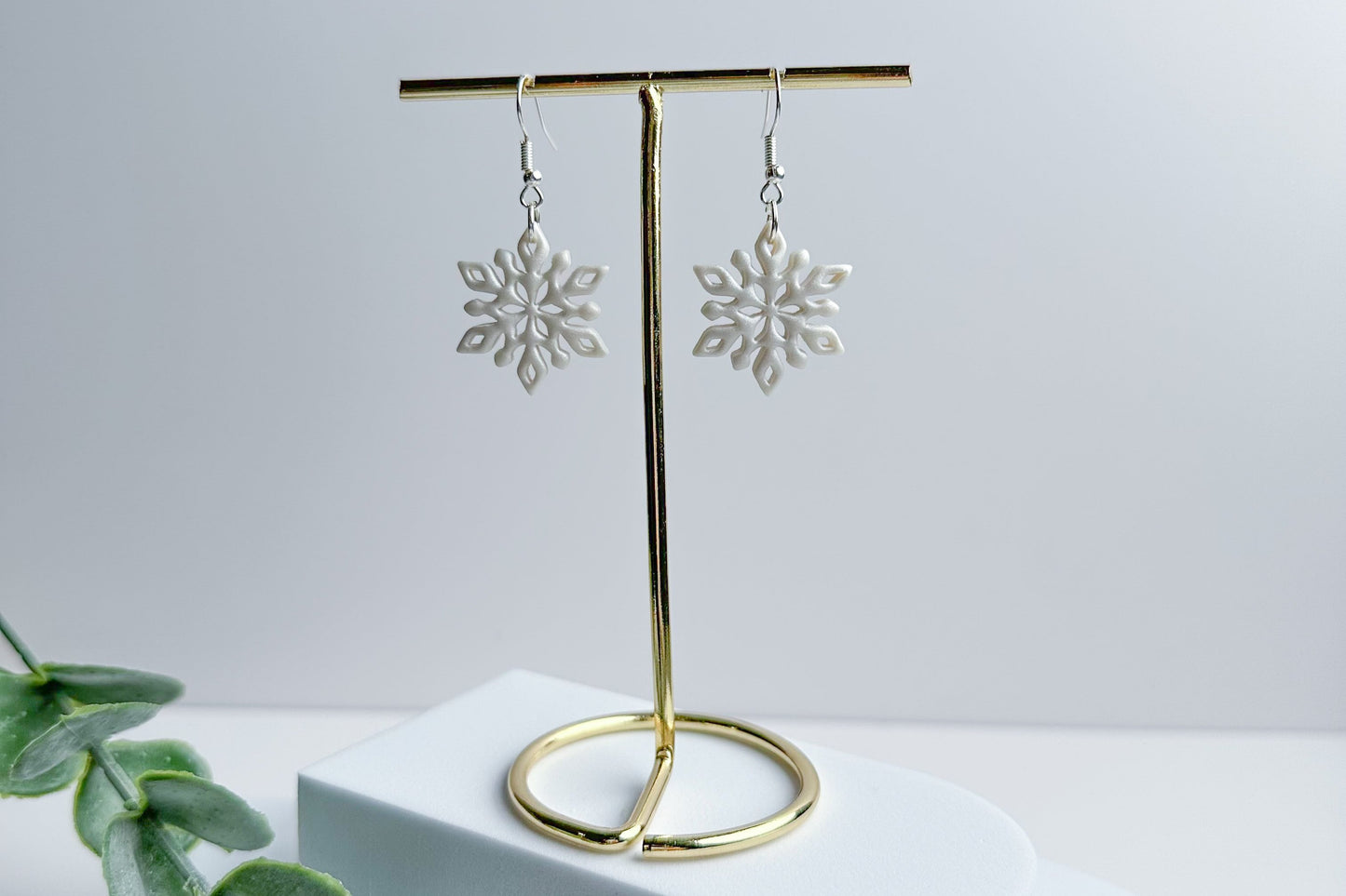 White ceramic snowflake earrings with silver hooks by Purely Clayful.